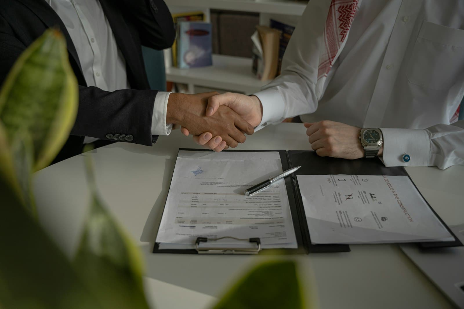 Two executives shaking hands over signed agreements