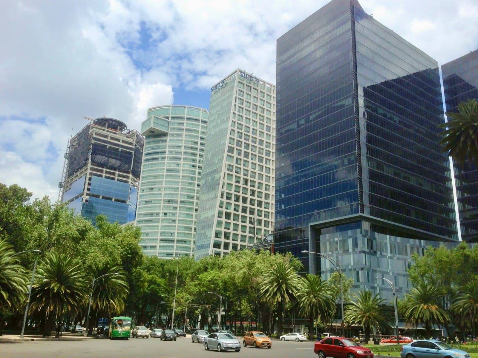 Glass office towers along Paseo de la Reforma in Mexico City's financial and business district, with a palm-lined boulevard and traffic below