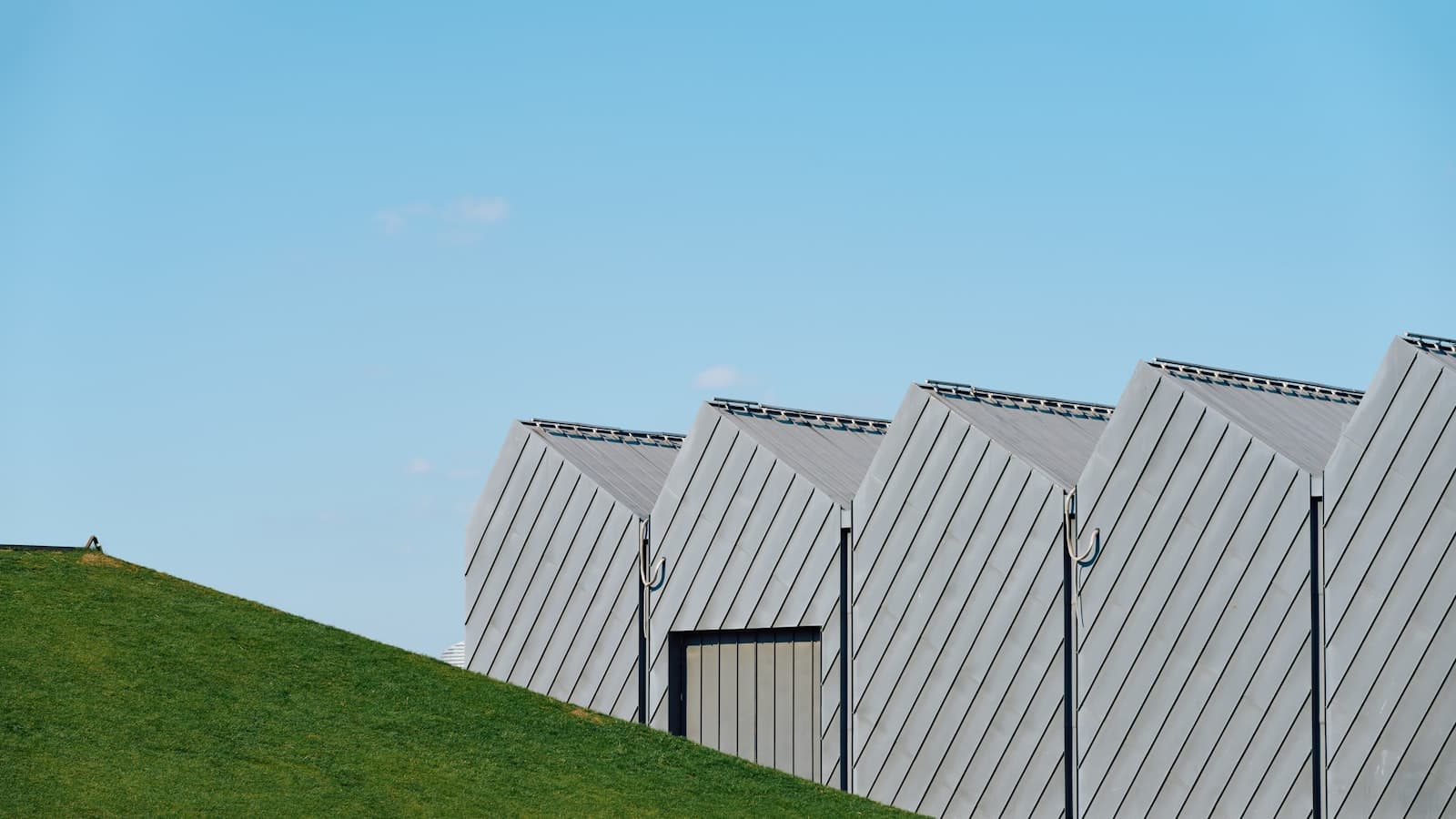 Modern sawtooth-roof manufacturing building against a clear sky, the kind of industrial-park facility a shelter provider operates for manufacturers in Mexico