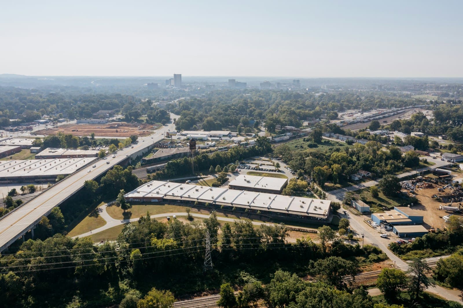 Aerial view of low-rise industrial buildings beside a highway and tree cover, the kind of park setting a manufacturer weighs when choosing a shelter provider