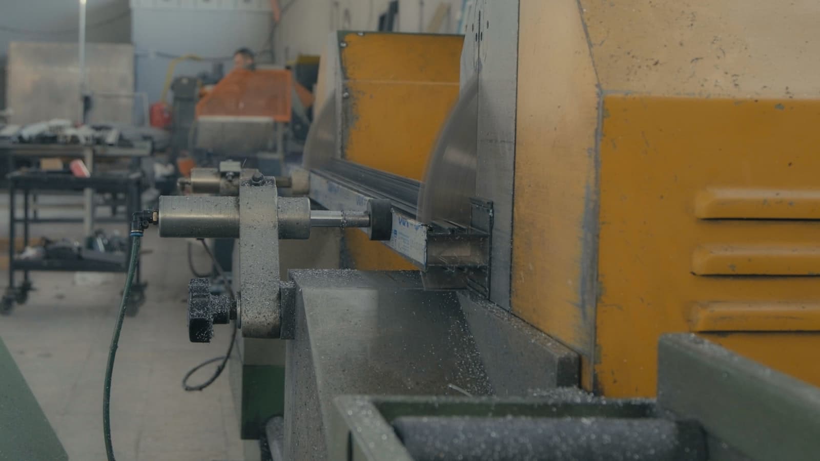 Metalworking machinery on the factory floor of a maquiladora manufacturing facility in Mexico, with an operator working in the background