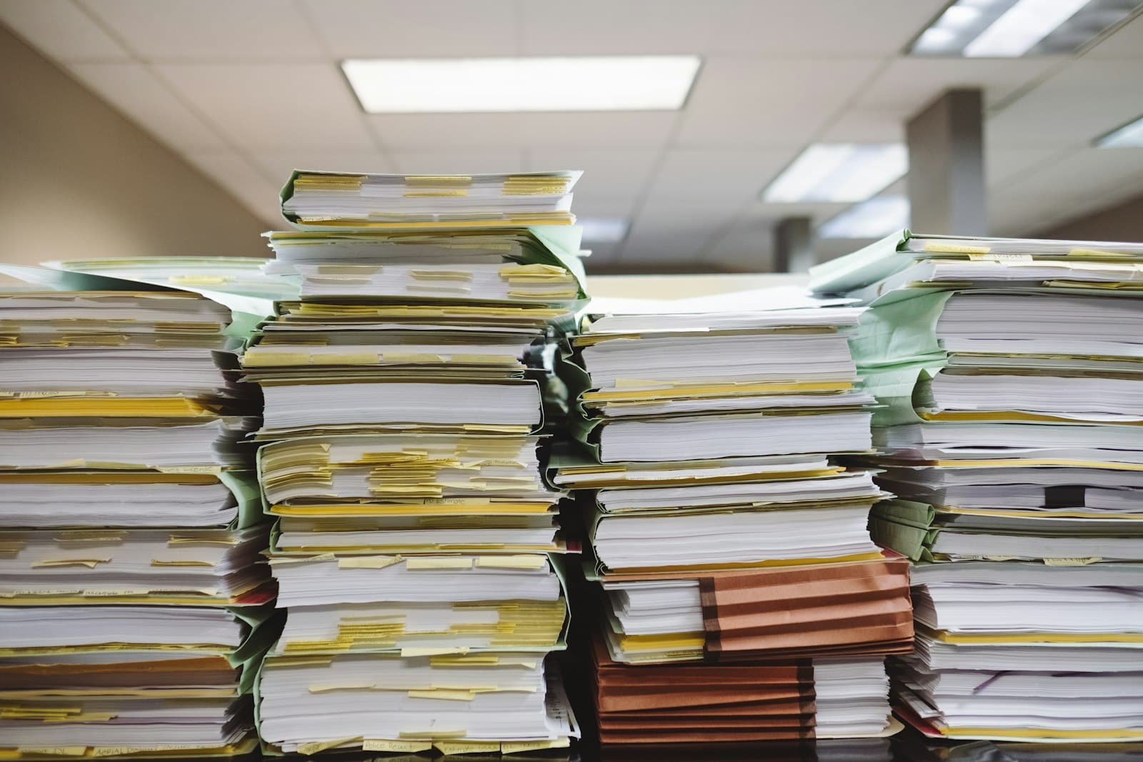 Stacks of tabbed files and folders on an office desk, the documentation behind a maquiladora's annual safe harbor filing