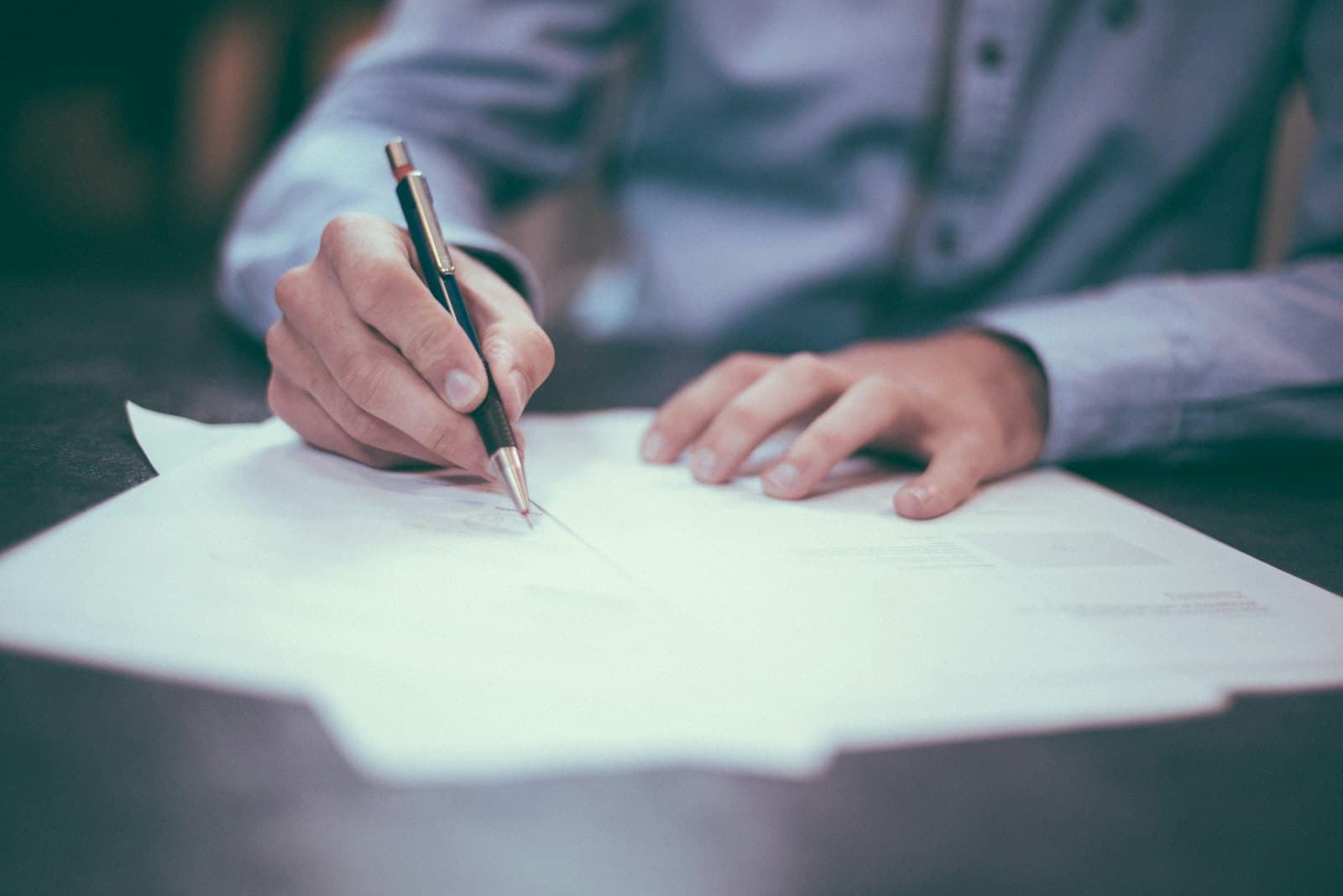 Executive signing corporate tax and compliance paperwork at a desk, representing the layered tax obligations foreign companies face when operating in Mexico