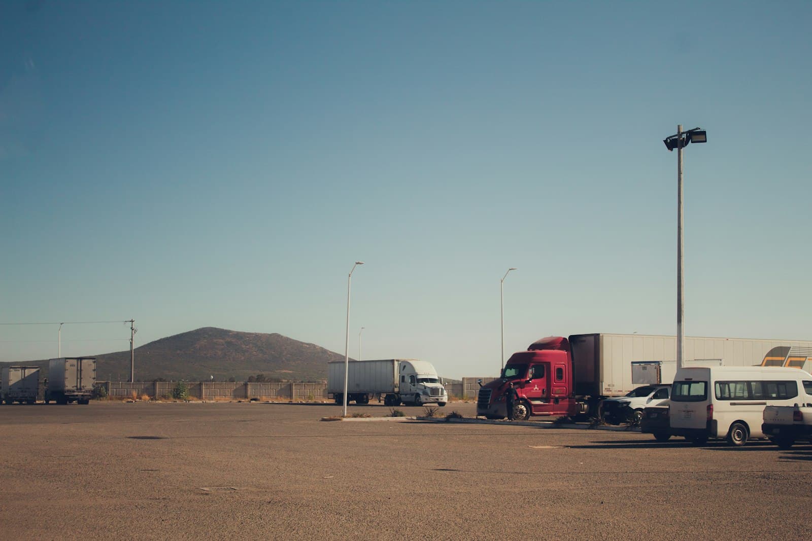 Tractor-trailers and box trailers parked in a walled freight yard in Querétaro, the Bajío manufacturing hub where every imported input carries a declared value