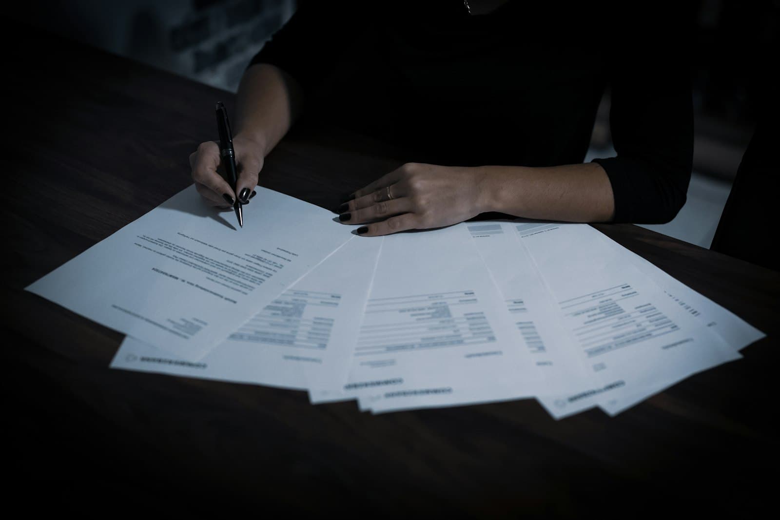 Hands signing formal incorporation documents fanned across a desk, as a foreign company formalizes its Mexican entity structure before a notario público