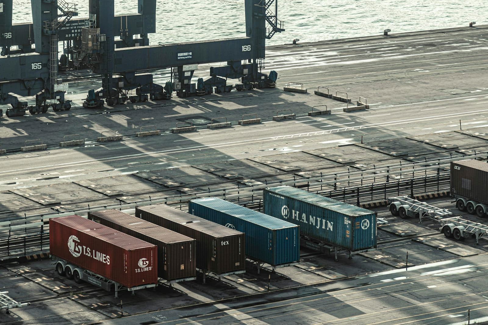Asian shipping line containers waiting on chassis on a port apron, the point where an input either pays a duty or defers it