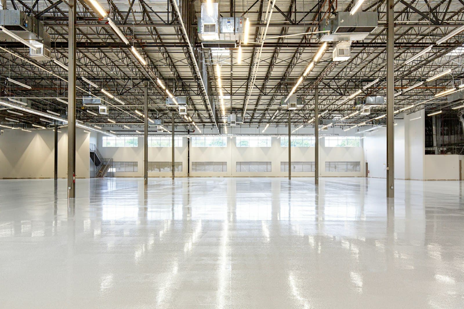 Empty modern manufacturing warehouse interior with polished concrete floor and exposed steel roof trusses, ready for a foreign manufacturer to operate under a shelter provider in Mexico