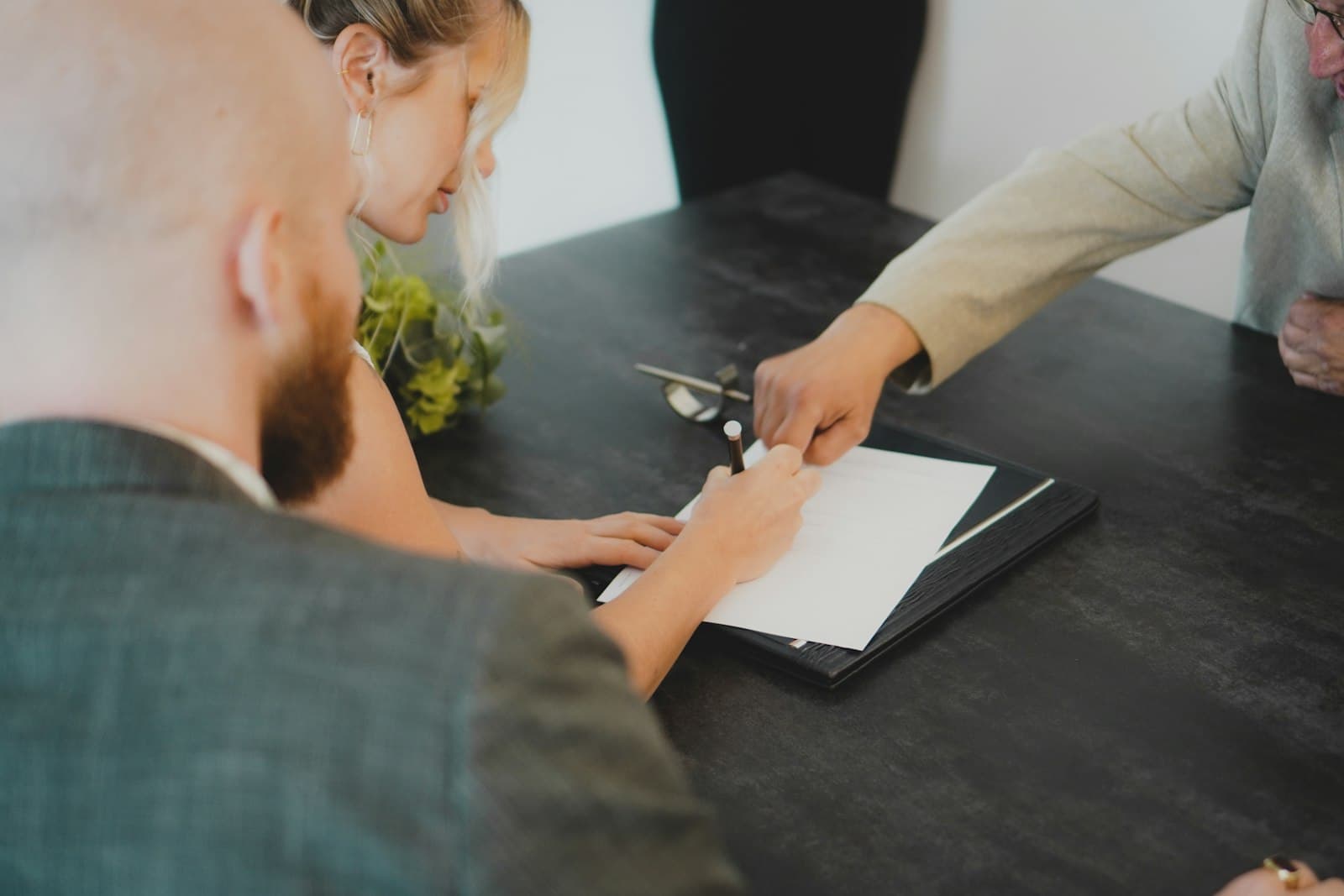 Founders signing incorporation documents across a desk as an advisor guides them, illustrating formalizing a company in Mexico before a notario