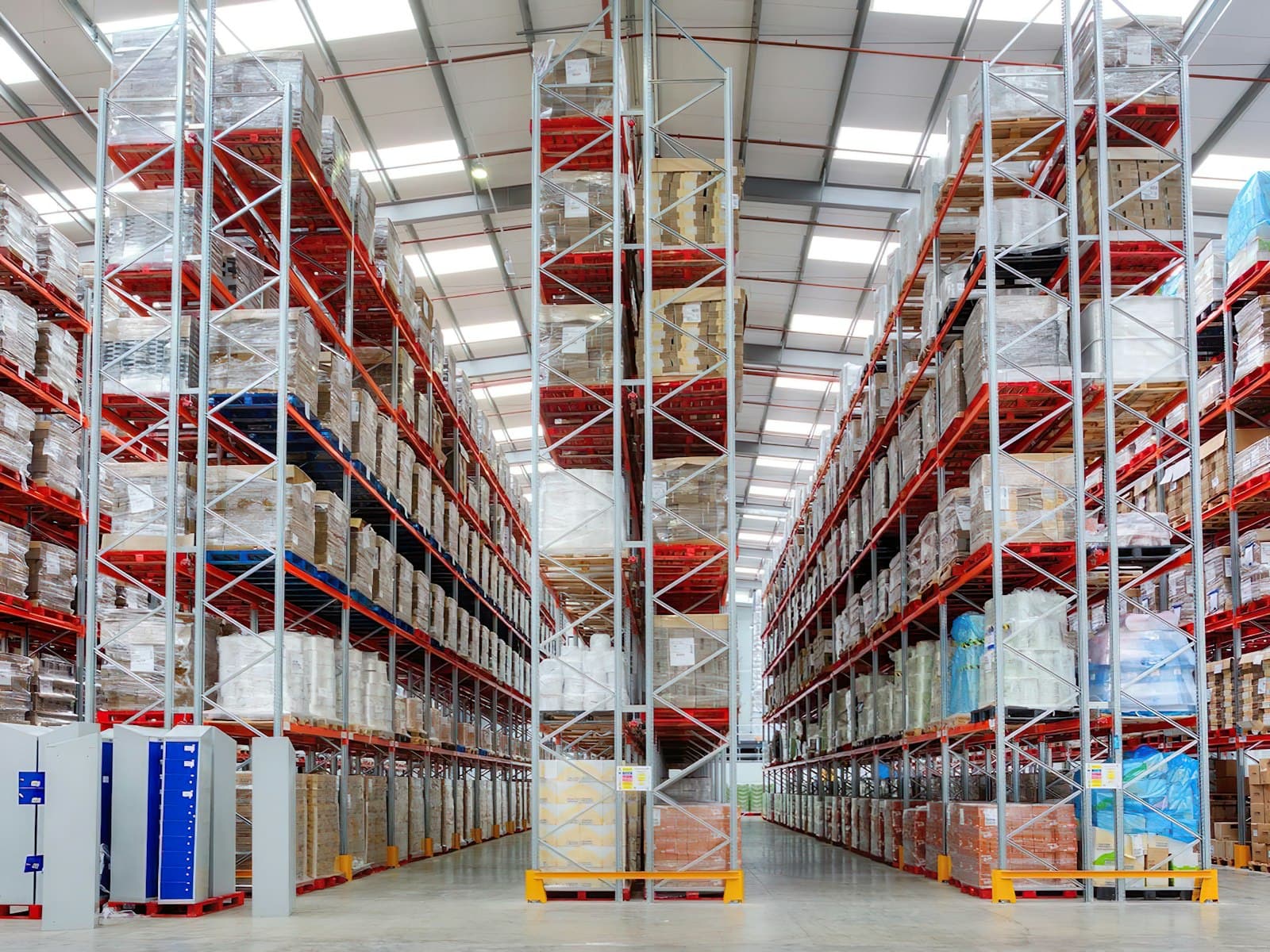 Tall pallet racking stocked with shrink-wrapped goods along the aisle of a distribution center, the kind of shelter-provided facility a manufacturer weighs when choosing between Tecma and Tetakawi in Mexico