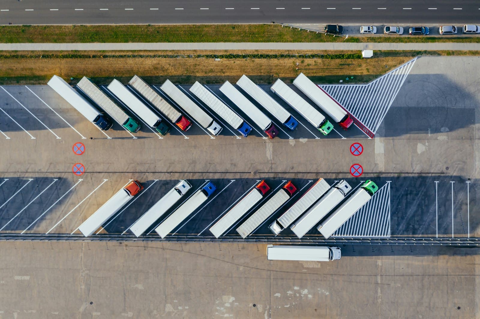 Aerial view of freight tractor-trailers staged in rows at a cross-border logistics yard, the kind that moves vehicles and auto parts through the Mexico-US supply chain governed by USMCA rules of origin.