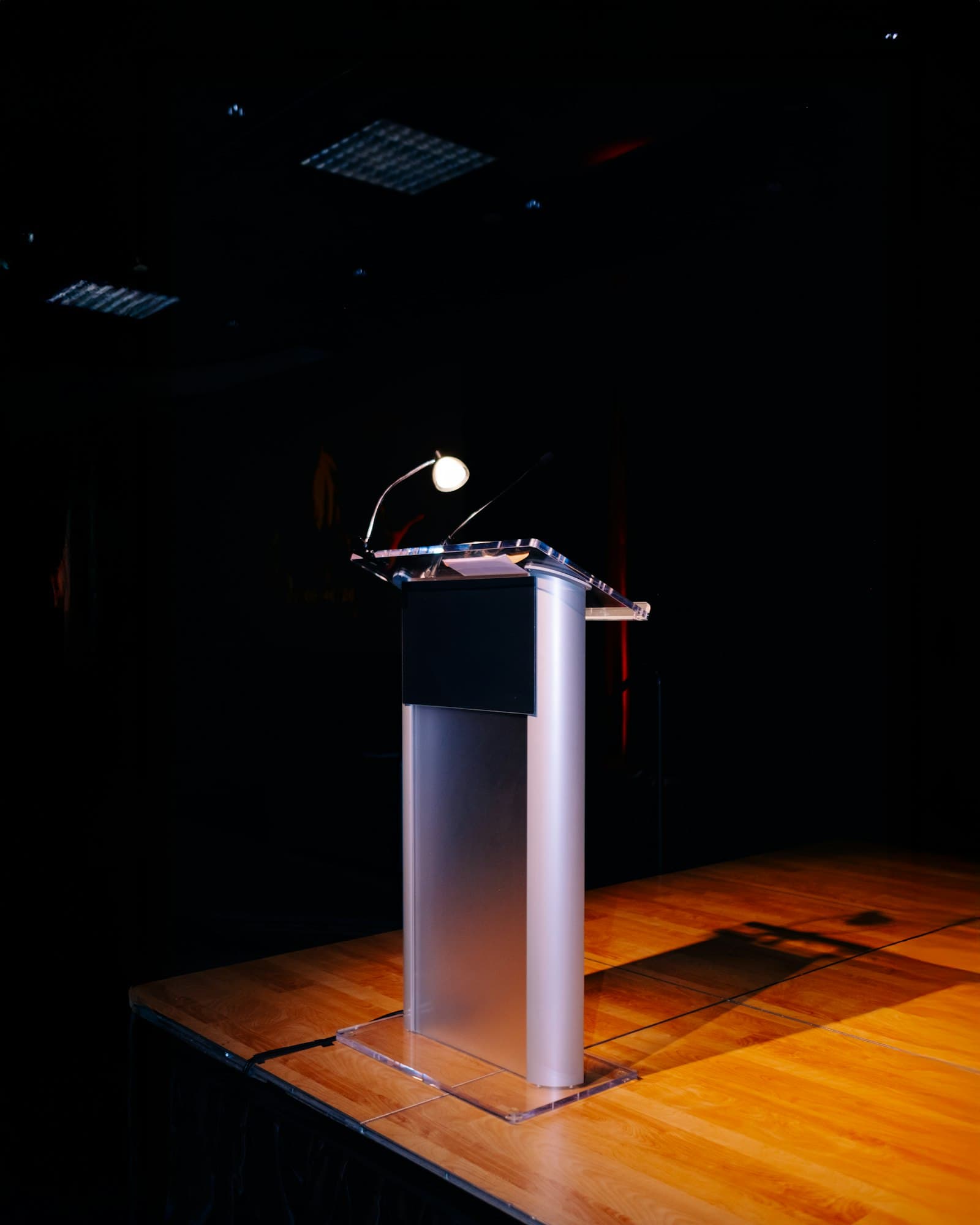 An empty press conference lectern with a microphone under a single stage light, evoking the July 20 US-Mexico USMCA round in Mexico City