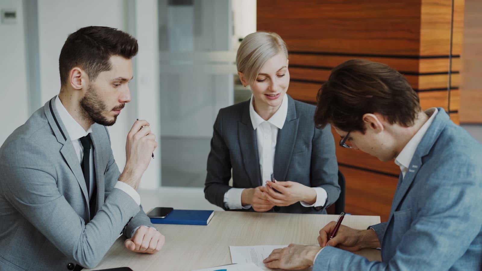 Executives signing a partnership agreement across a table in a modern office while an advisor reviews the terms, the moment a SEDECO incentive package is formalized into an executed convenio.